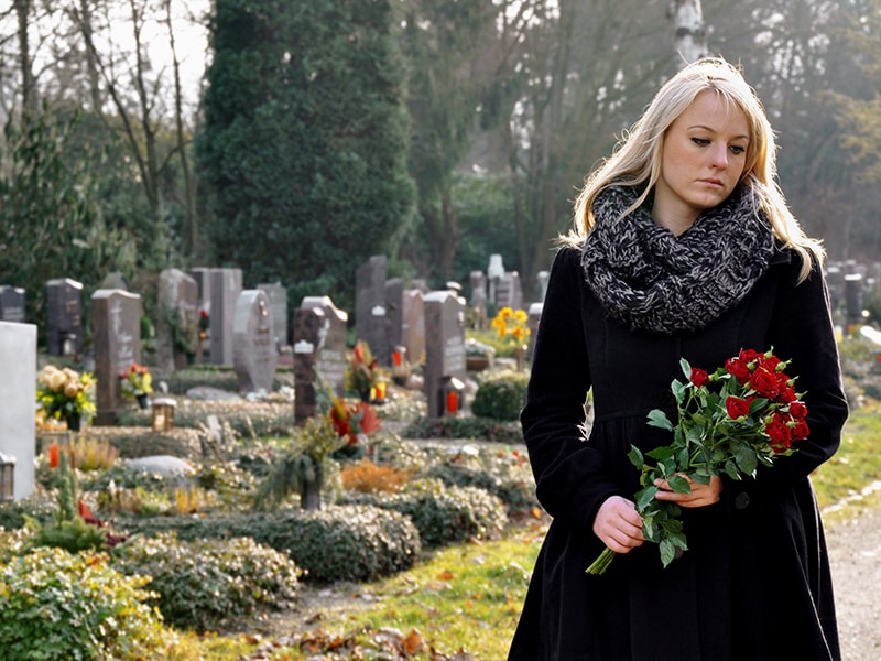 Frau auf dem Friedhof in Werl mit einem Rosenstrauß in tiefer Trauer 